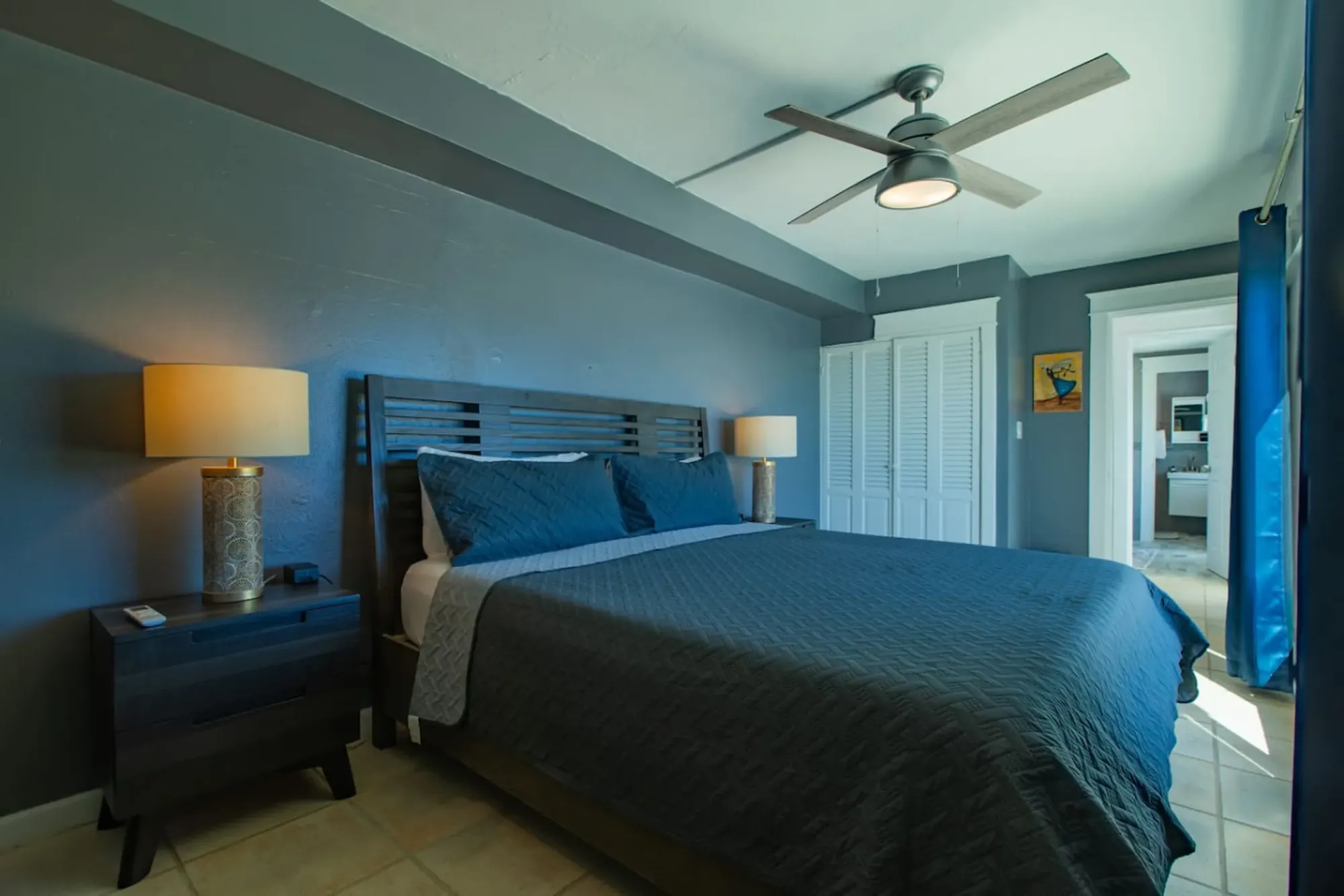 A bedroom with teal linens and an en-suite bath