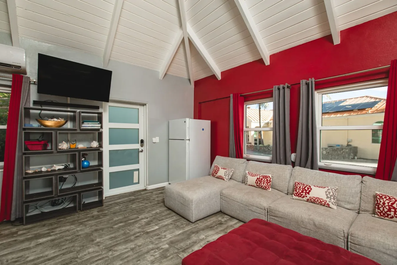 The guest cottage living room with a gray sectional and red accent wall