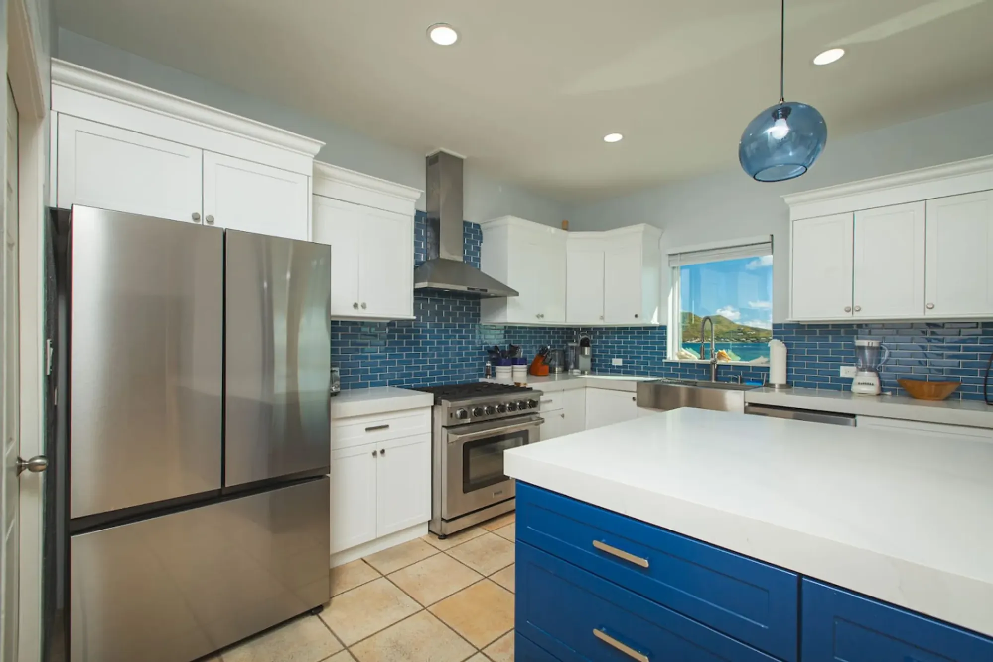 The chef's kitchen with a blue island and a sea-view window